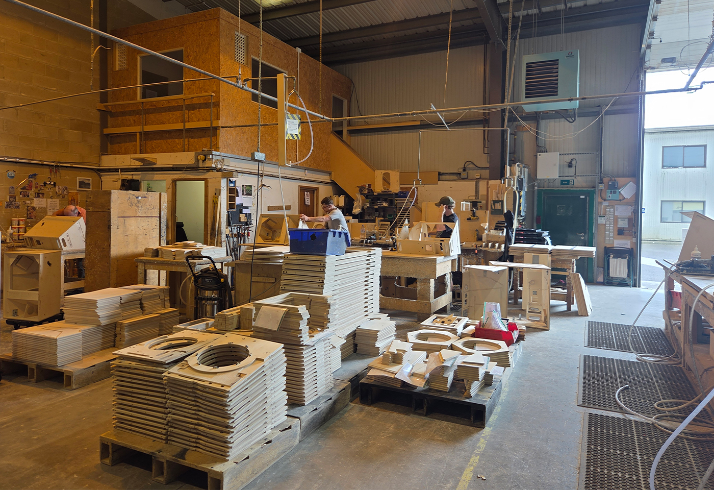 Hand assembly of a speaker cabinet at the Sarivale workshop, fitting internal bracing and hardware.